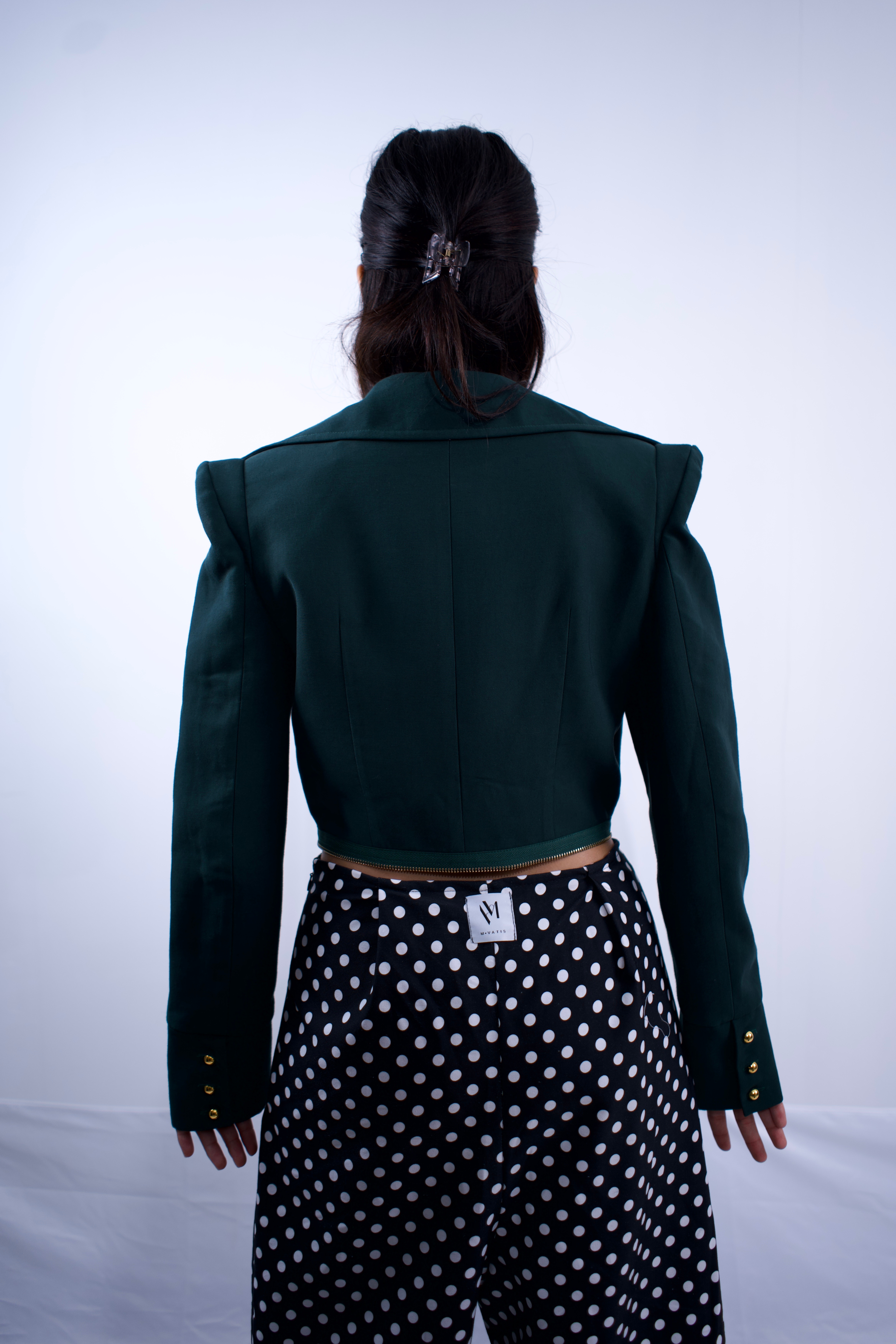 Person wearing a green jacket and polka dot pants on a white background