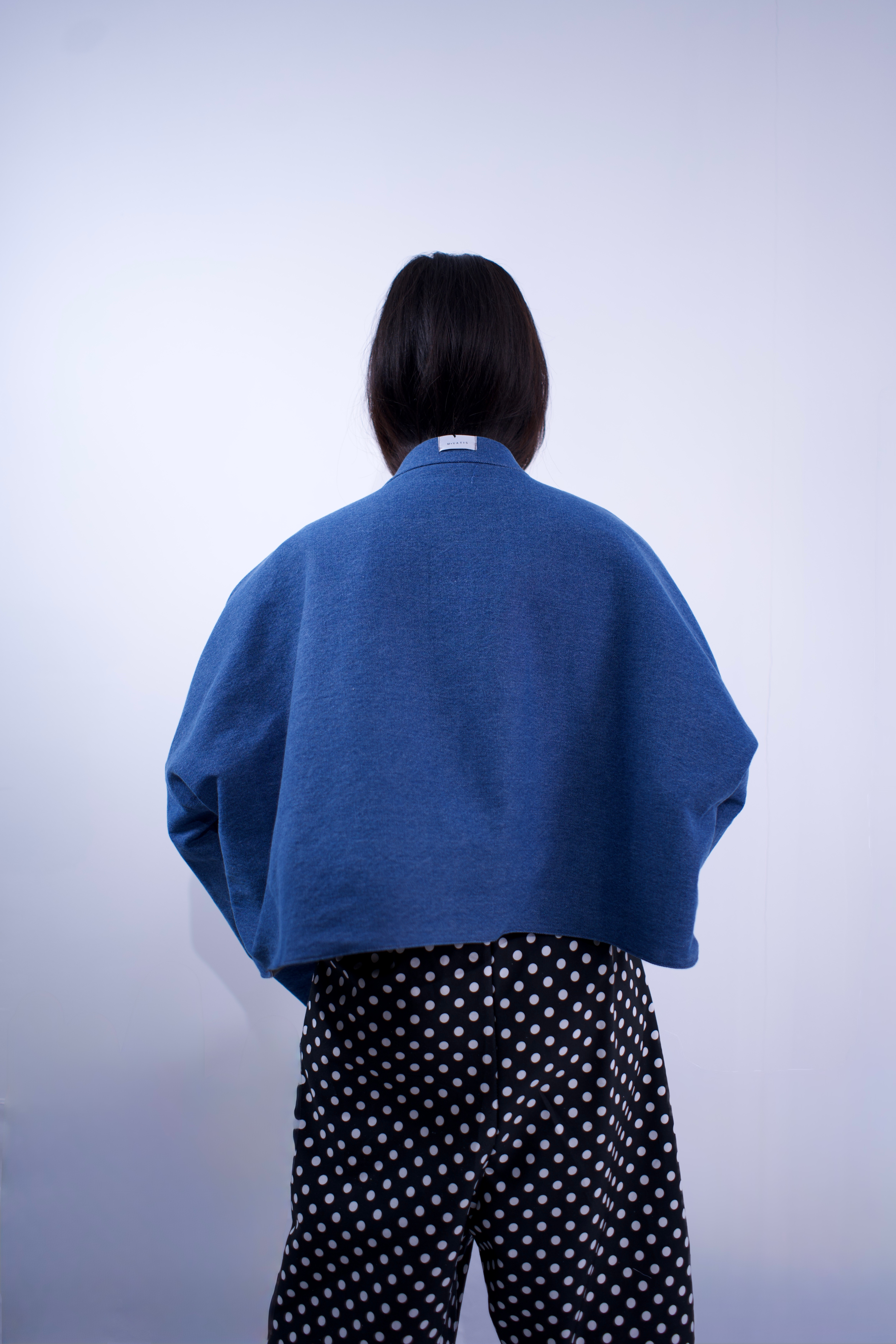 Person wearing a blue sweater and polka dot pants against a white background