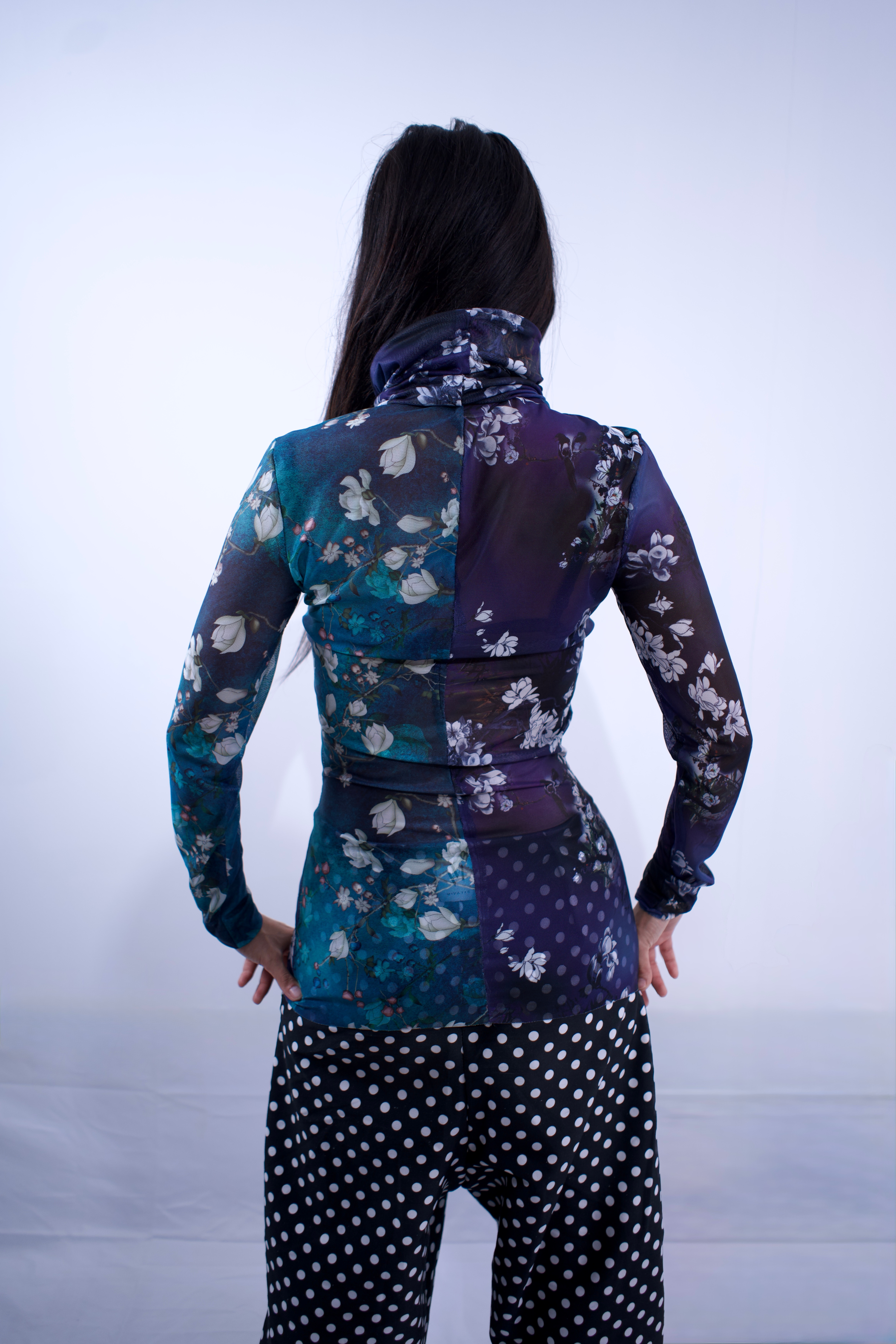 Person wearing a floral long-sleeve top and polka dot pants on a white background