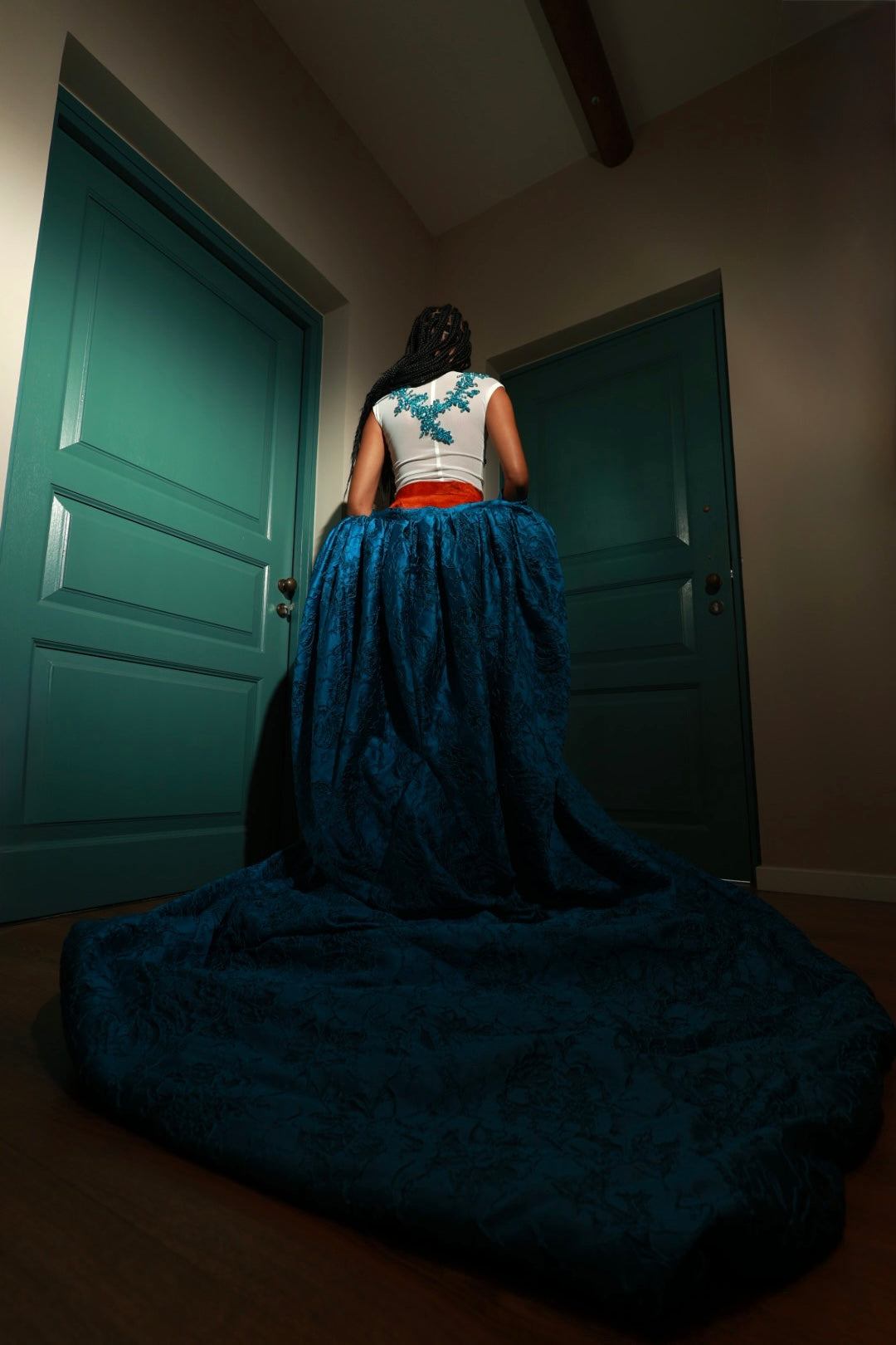 Designer evening gown with teal floral embroidery on a sheer mesh bodice, burnt orange velvet waistband, and a voluminous sapphire blue brocade skirt—perfect for formal events, galas, and red carpet occasions.”
