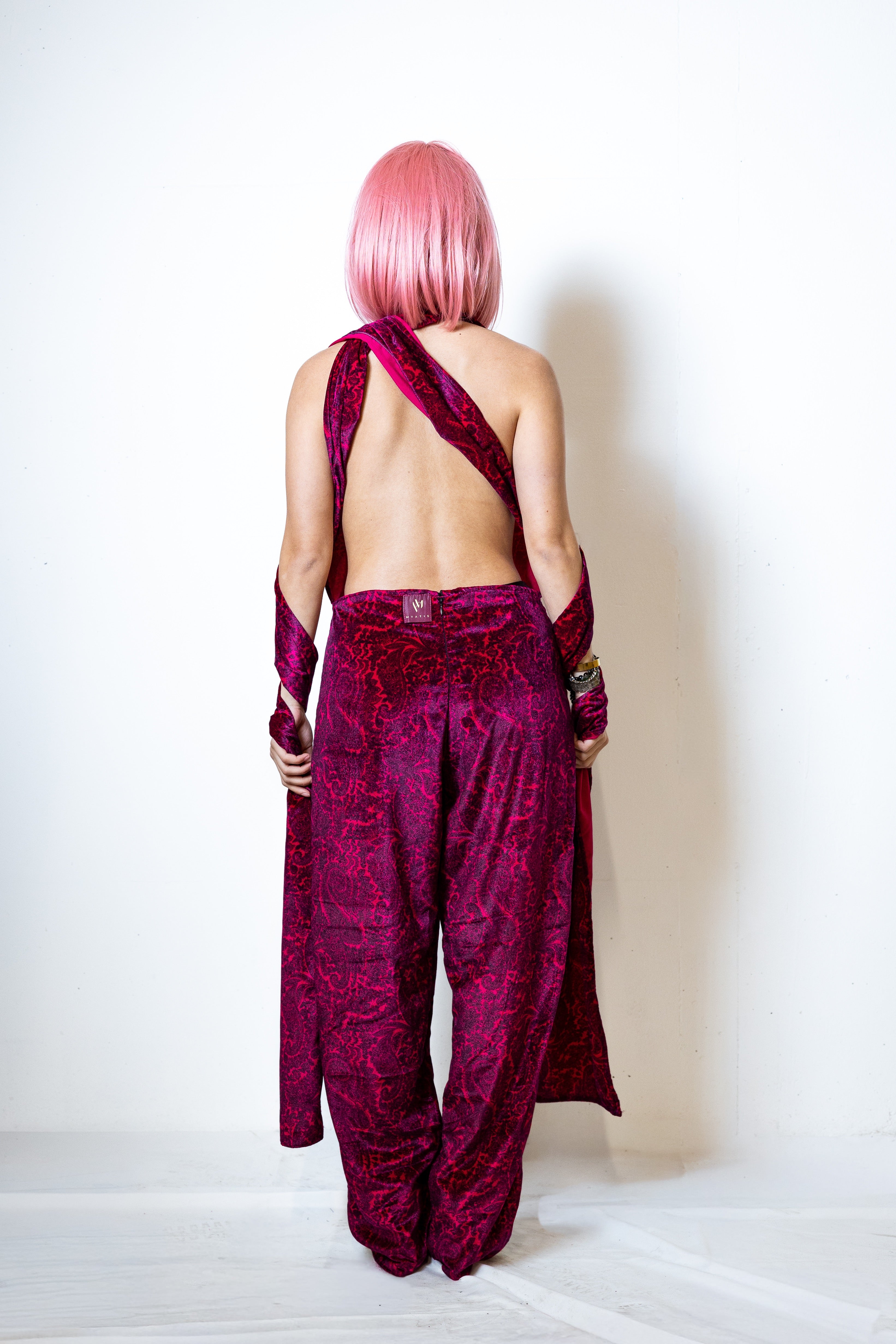 Person wearing a vibrant pink outfit with a matching wig on a white background