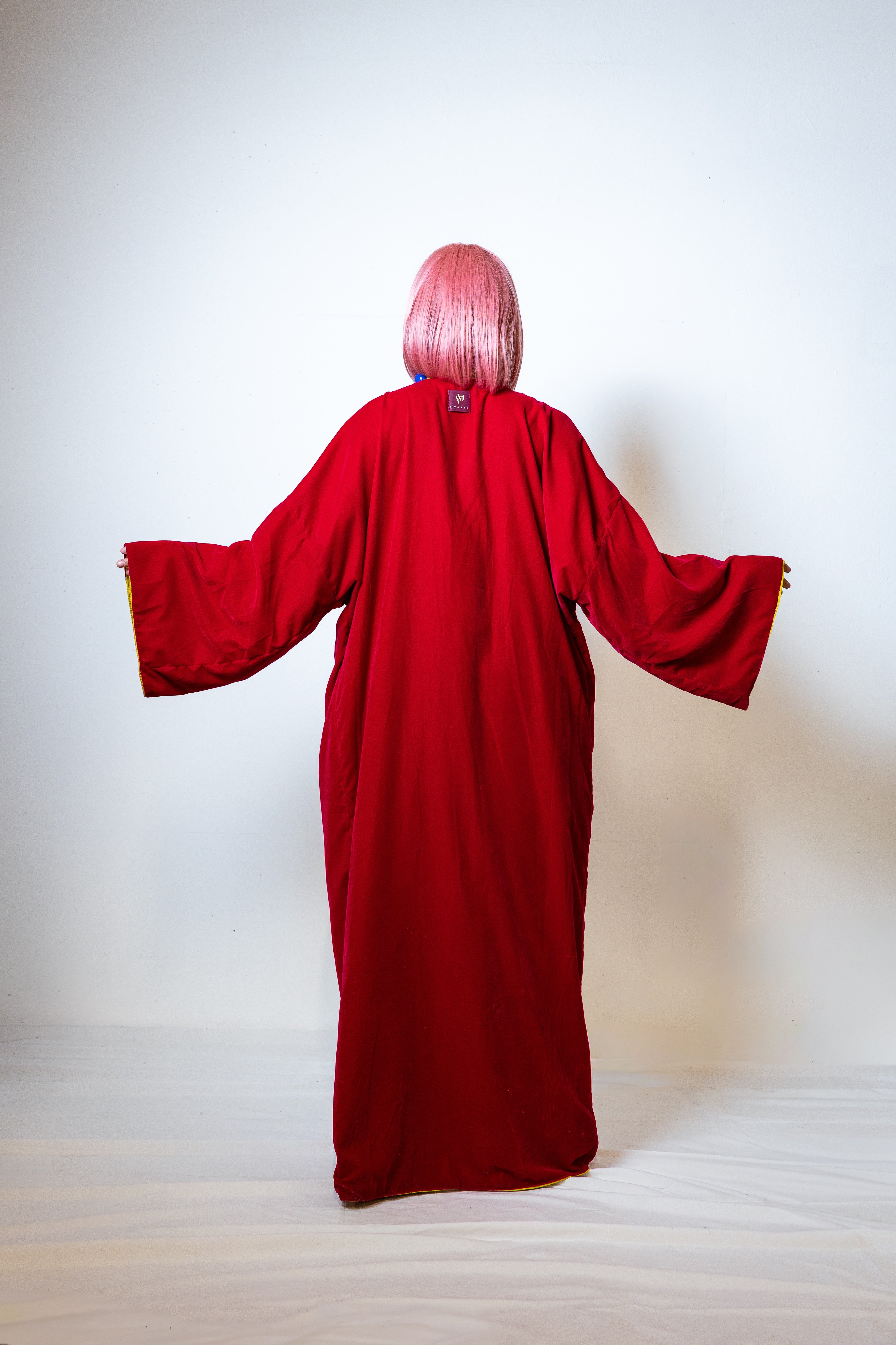 Person wearing a red robe with long sleeves on a white background