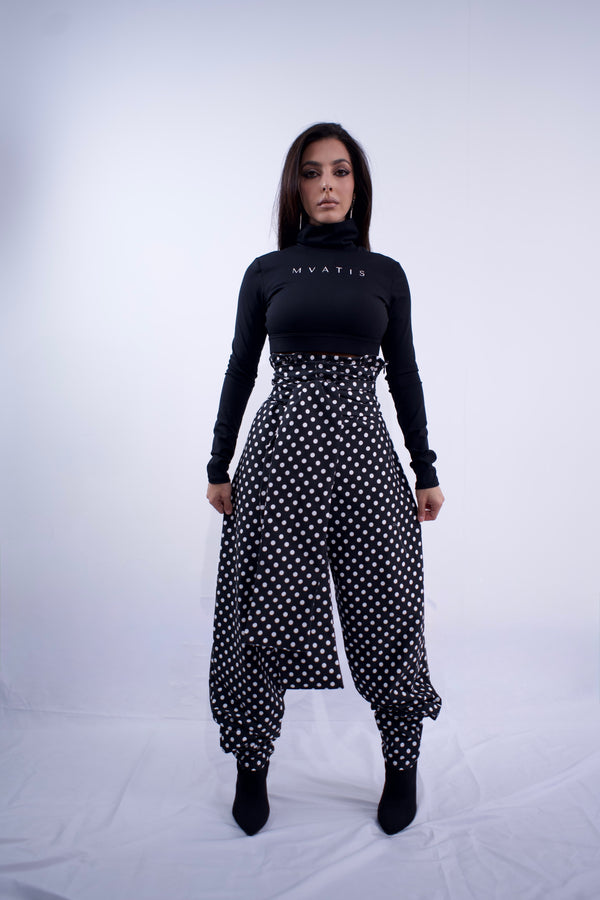 Woman wearing a black turtleneck and polka dot pants on a white background