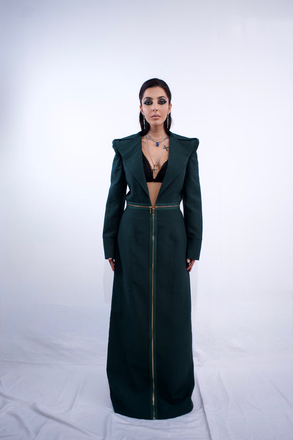 Woman wearing a long dark green dress with a high collar and zipper on a white background