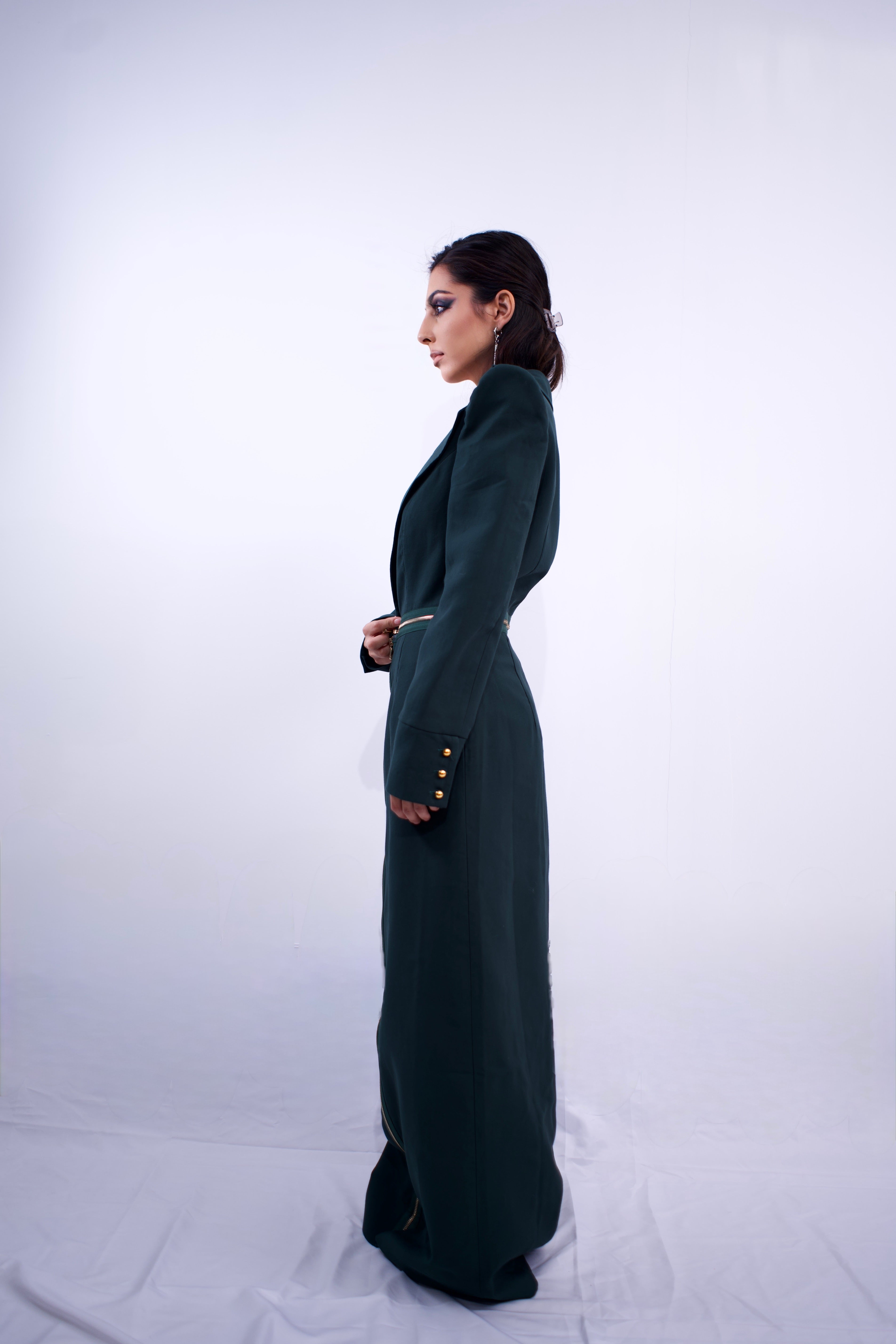 Woman wearing a long dark green dress against a white background