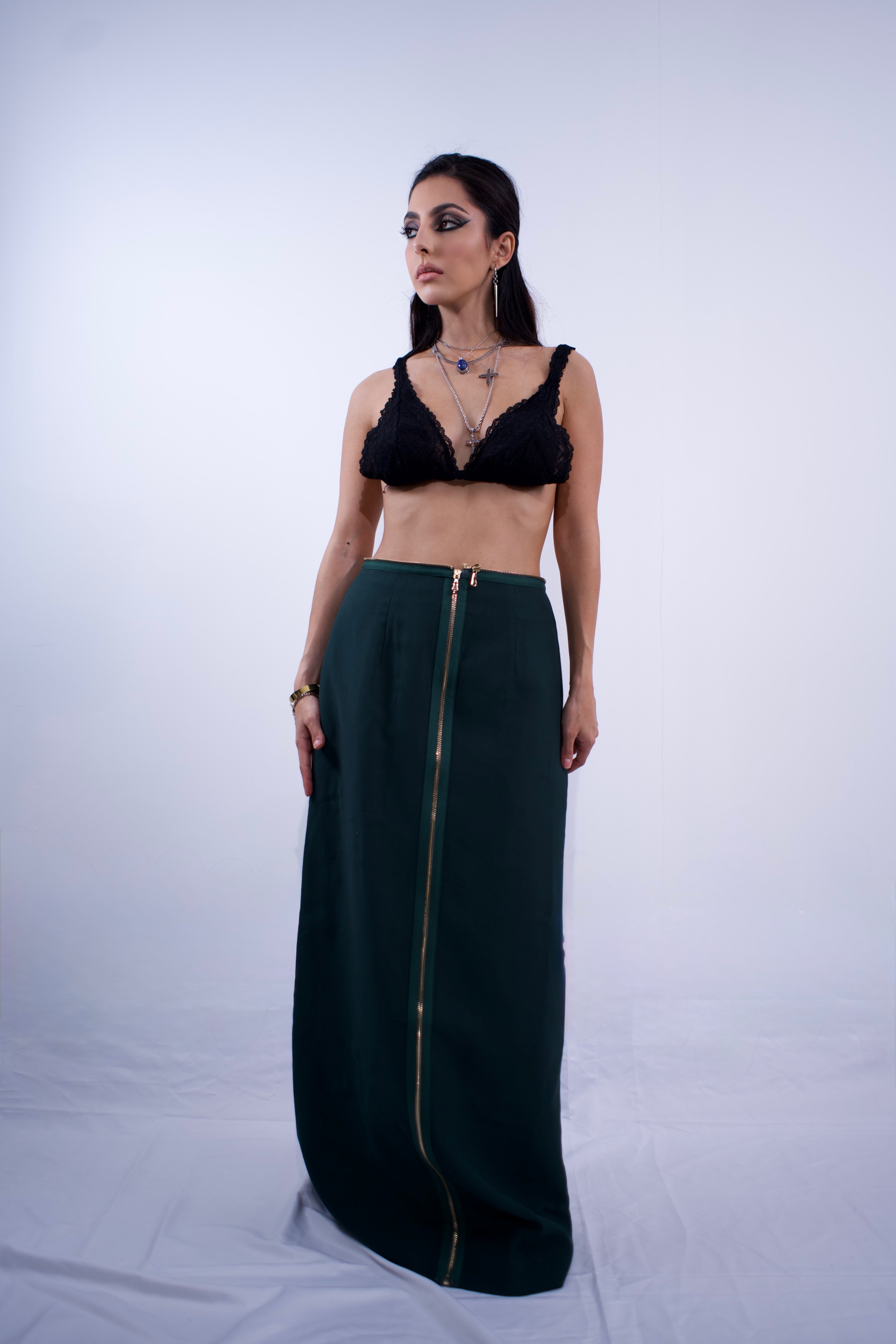 Woman wearing a black bralette and green skirt on a white background