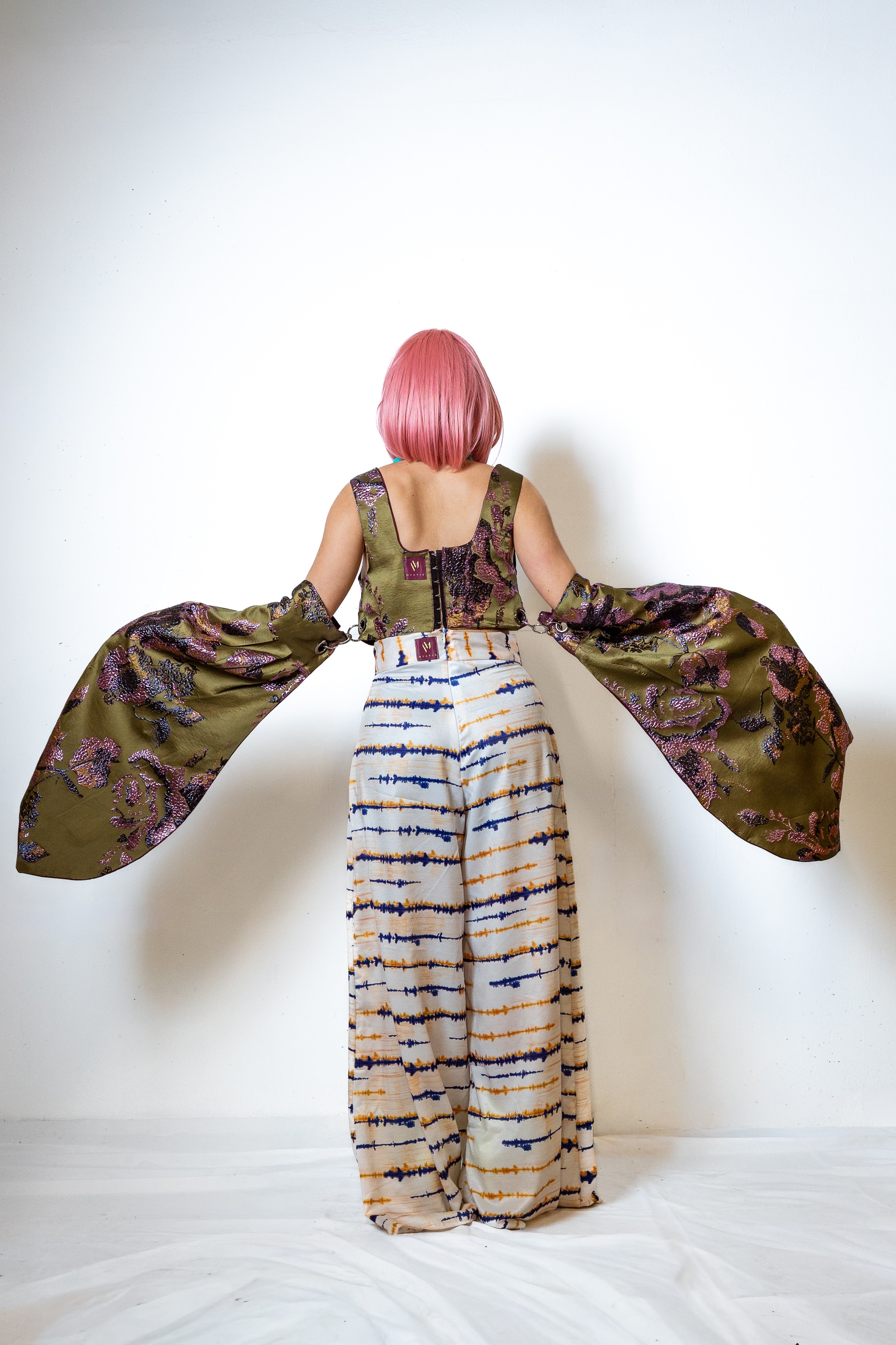 Person wearing a green patterned outfit crop top african inspired top with a white background
