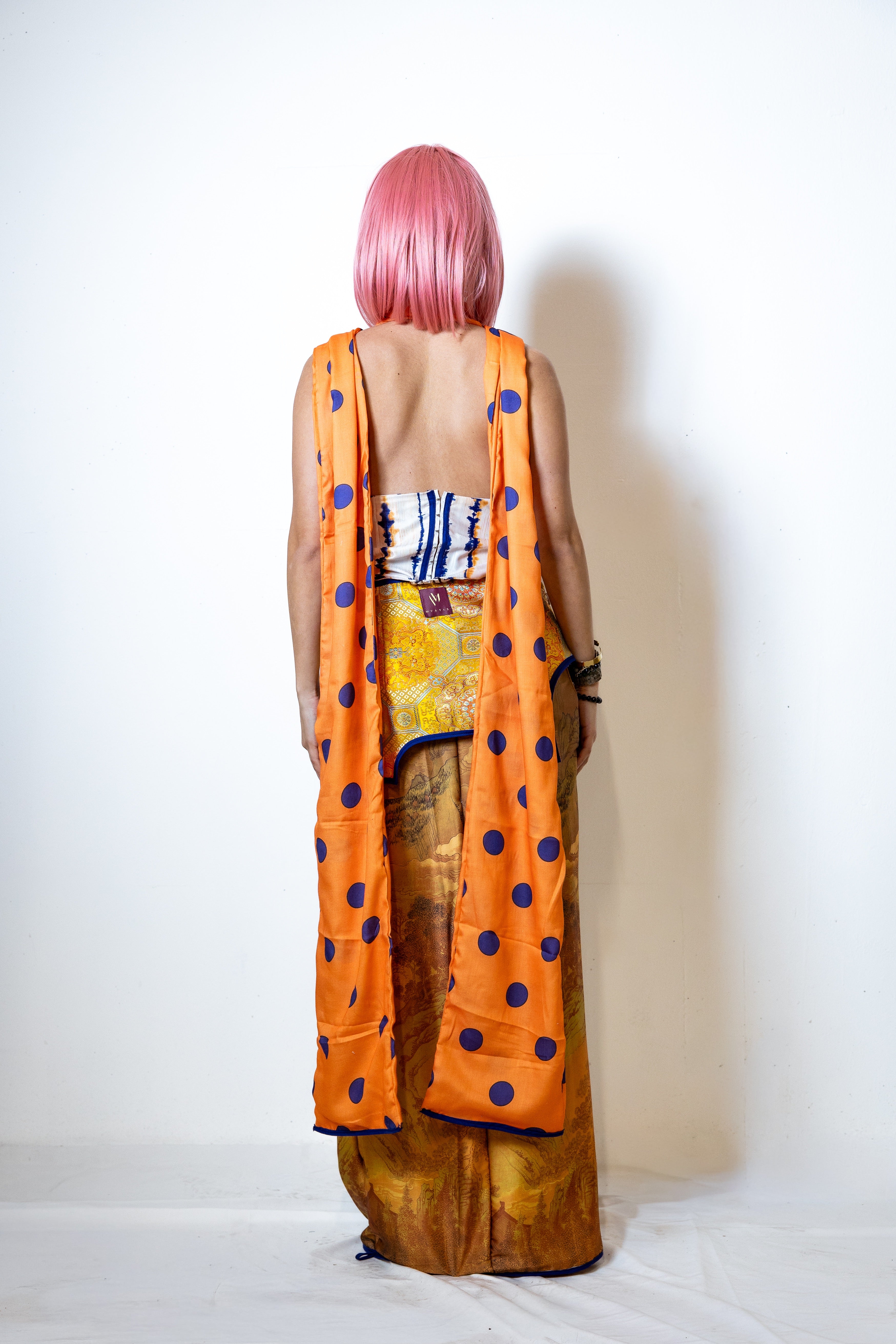 Person wearing an orange polka dot outfit with a white background