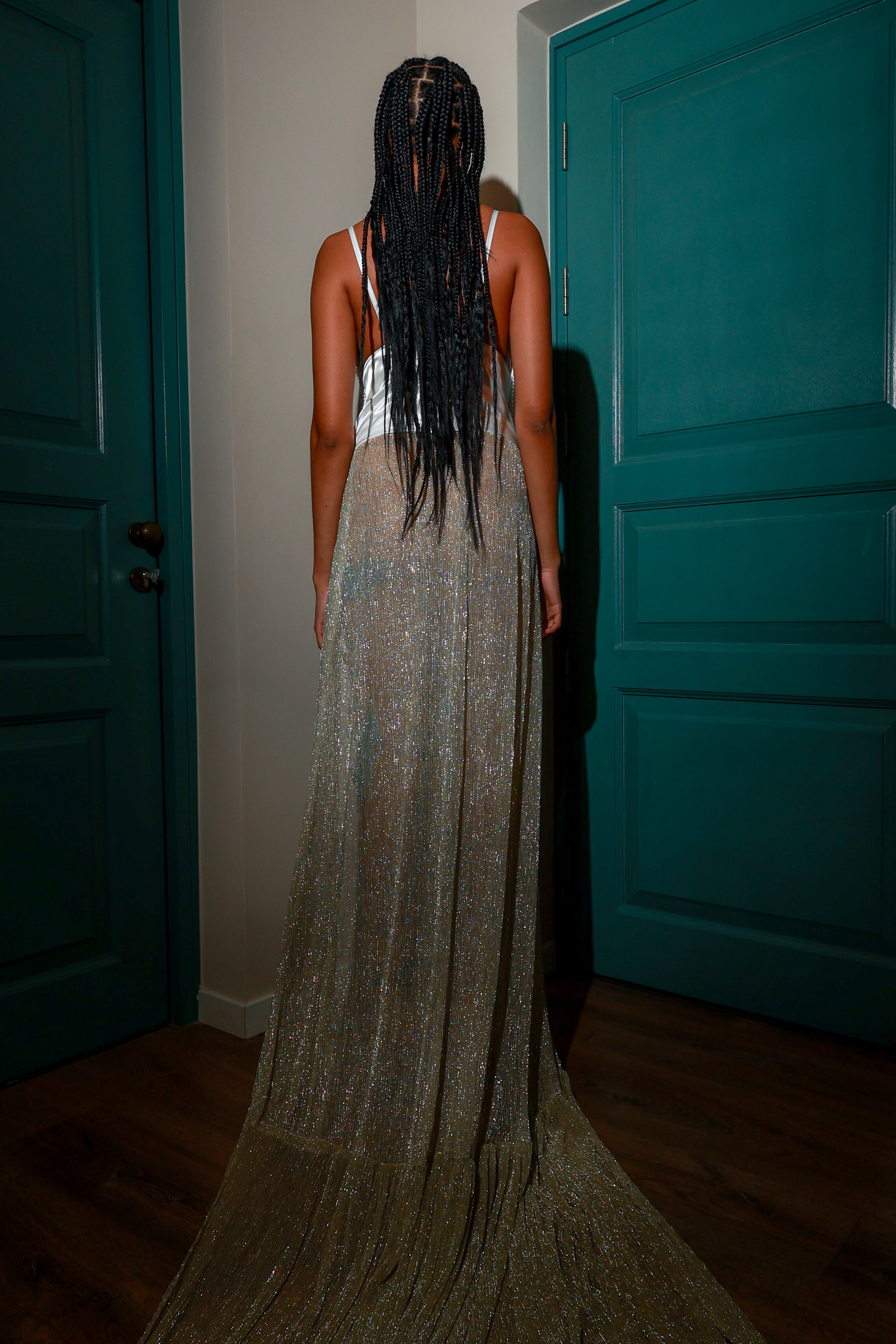 Model wearing a handcrafted pearl-embellished sculptural gown with metallic sheer skirt, side slit adorned with teal applique embroidery, and long dramatic train — luxury couture fashion design.
Front view of pearl beaded sculptural dress with shimmering lurex skirt and thigh-high slit featuring turquoise detailing, styled for runway or red carpet.